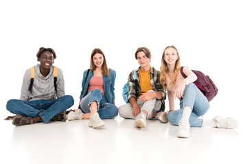 Obraz premium Smiling multicultural teenagers with backpacks looking at camera on white background