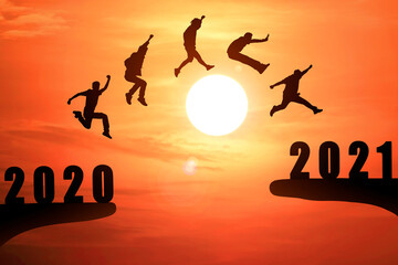 Silhouette group of young mans jumping between 2020 and 2021 years with beautiful sunset at the sea-use for news year and concepts for business and target.