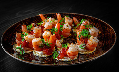 set of Appetizer canape with shrimp, cheese and sauce on a small loaf of bread in plate on black wooden table