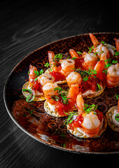 set of Appetizer canape with shrimp, cheese and sauce on a small loaf of bread in plate on black wooden table