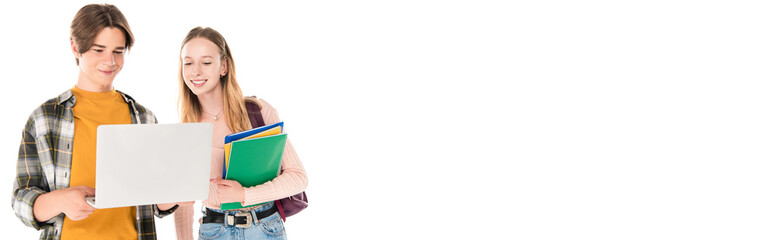 Panoramic crop of teen girl with backpack and notebooks standing near smiling friend with laptop isolated on white