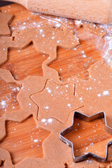 Shortbread dough for gingerbread cookies rolled on the wooden board. Cutting out star shaped cookies
