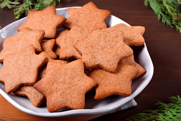 Gingerbread star cookies on the ceramic plate on the wooden table. Christmas pastry
