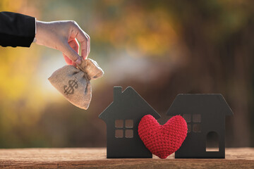 Businessman hand hold the money bag present to the home model and red heart put on the vintage...