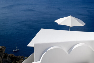 White building and white umbrella on a background of blue sea. Santorini. Greece.