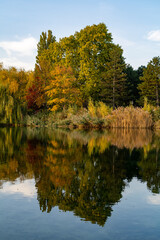 Reflection of autumn trees with multi-colored foliage in the calm waters of the lake