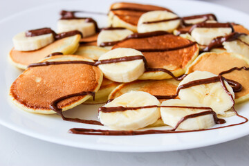 Fototapeta na wymiar Mini pancakes with fruit drizzled with chocolate and honey