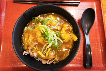 Japanese curry rice with beef in a black bowl on table with nature light through the window.