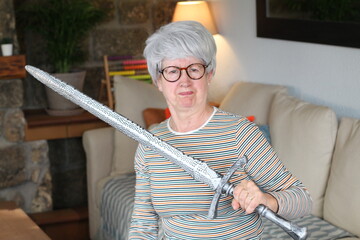 Senior geek holding a sword at home 