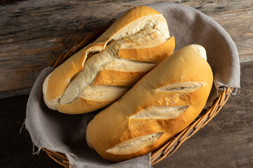 
homemade french bread in a wicker basket with a gray rustic cloth on a wooden table