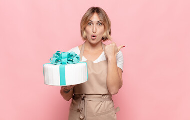 young blonde woman looking astonished in disbelief, pointing at object on the side and saying wow,...