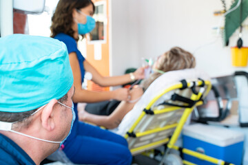 Female nurse paramedic with face mask helping a patient with respiratory system in ambulance during pandemic © bulentbaris