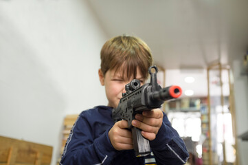 Little boy plays with assault rifle. Toy guns concept