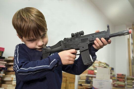 Little boy plays with assault rifle. Toy guns concept