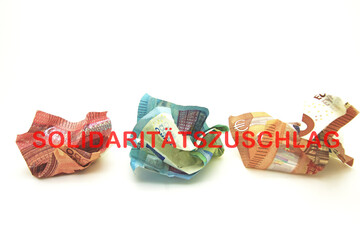 Zerknüllte Euro Banknoten mit Text Solidaritätszuschlag.