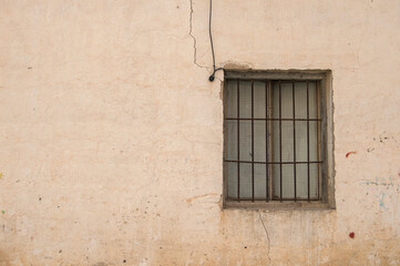 old chipped brick facade of a warehouse with a window 