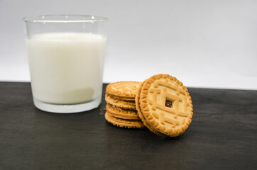 a glass of milk and cookies on a black wooden table.