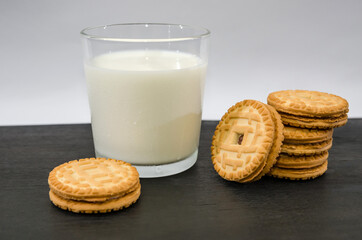a glass of milk and cookies on a black wooden table.