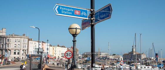 UK. 2020. A sign for the railway station and coastal trail at the yacht marina on the Ramsgate...