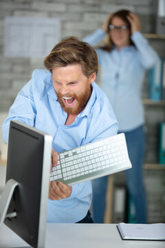 angry businessman smashes computer with keyboard
