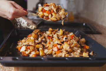 Large spoon with stewed vegetables over baking sheet