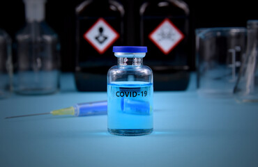 COVID-19 vaccine with syringe stock images. Coronavirus vaccine and injection isolated on a blue background images. Glass laboratory equipment with warning symbols. Laboratory accessories stock photo