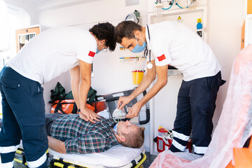Male first aid workers giving CPR to someone who has had a heart attack in an ambulance
