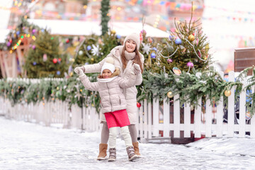 Cheerful family, mother and little girl having fun on Christmas market.