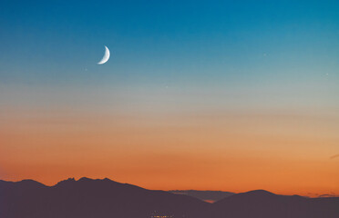 Beautiful panoramic view of the mountains with moon on the starry sky.