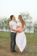 Happy moments of pregnancy. A loving husband with his pregnant wife in the fresh air away from the city