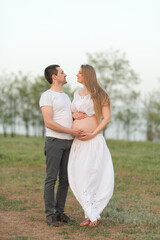 Fototapeta premium Happy moments of pregnancy. A loving husband with his pregnant wife in the fresh air away from the city