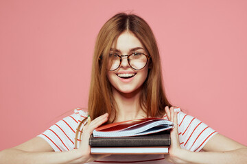 Young female student with books on pink background glasses on face education institute cropped view