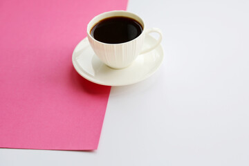 Obraz na płótnie Canvas White porcelain cup with black coffee on the pink and white texture background. Simple template for your postcard and design, place for text