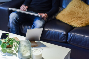 Man working at home from desk in a living room with tablet and note pad