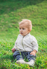 Cute surprised baby sitting on a meadow