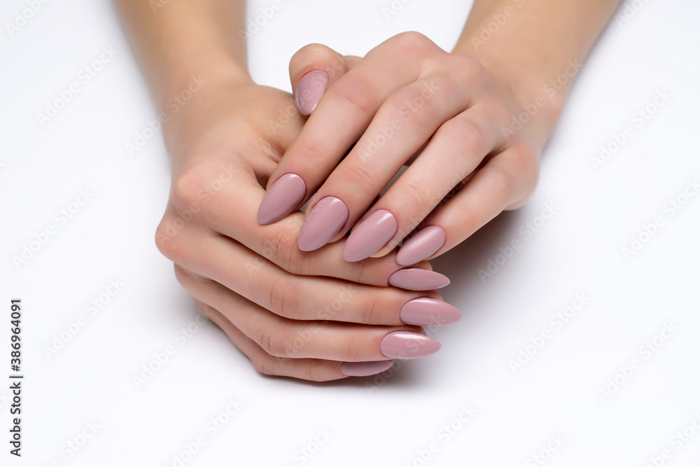 Wall mural Nude, beige gel extended manicure on sharp long nails close-up on a white background