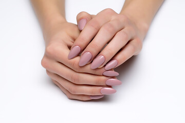 Nude, beige gel extended manicure on sharp long nails close-up on a white background