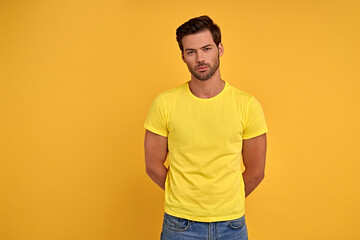 Fototapeta na wymiar Photo of masculine man in yellow basic t-shirt isolated over yellow background