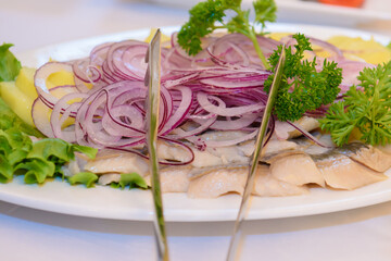 Blue onion with slices of herring on a plate. Festive appetizer at the Banquet.