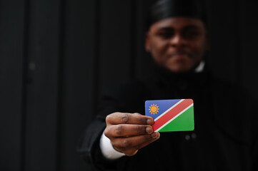 African man wear black durag hold Namibia flag at hand isolated dark background.