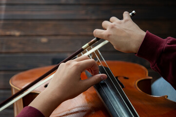 Musician with cello plays the strings with his hands