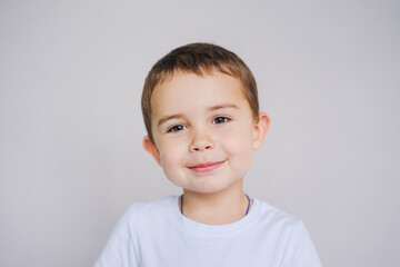Fototapeta premium Little boy smiling while looking into the camera. Close-up portrait of a Caucasian child.