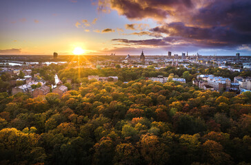 Aerial view of Riga city at colorful sunset. Impressive storm clouds over the city park in autumn...