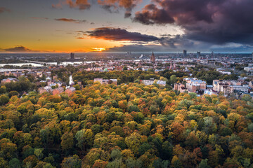 Aerial view of Riga city at colorful sunset. Impressive storm clouds over the city park in autumn colors. 