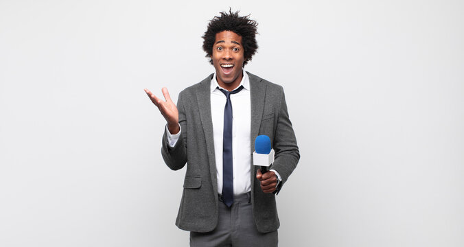 young black afro man feeling happy, excited, surprised or shocked, smiling and astonished at something unbelievable