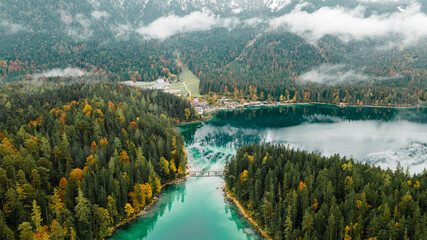 Autumn in the Bavarian mountains, Germany. Alps landscape with lake, bridge, clouds, forest, stones and reflection in turquoise water. View from above. Aerial drone outdoor photo.
