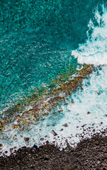 Turquoise waves and sea foam from above. Atlantic ocean coastline with cliffs, rocks and stones. Madeira island, Portugal. Aerial drone photography. Scenery outdoor background.