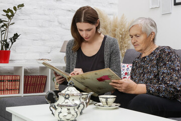 Grandmother looking at photo album with her granddaughter. Preserving family heritage concept.