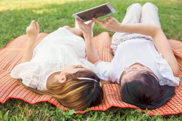 Mother and daughter using a digital tablet together lay on mat. Mother's Day. Picnic, family and kid concept. Educators during the outbreak. Online learners, Home Study, teacher.