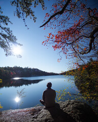 Sitting on rock at a reflective lake during the fall/autumn in october, november